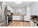 Modern kitchen with stainless steel appliances, white cabinets, and wood floors at 2900 Heathstead Pl # H, Charlotte, NC 28210