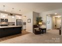 Open living space connecting to the kitchen with a comfortable recliner and view of hallway at 3156 Pinehills Way, Mount Holly, NC 28120