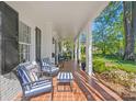 Spacious front porch featuring brick flooring, stately columns, comfortable seating, and manicured landscaping at 332 Hempstead Pl, Charlotte, NC 28207