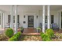 Inviting front porch with brick flooring, black door, stately columns, potted plants, and comfortable seating at 332 Hempstead Pl, Charlotte, NC 28207