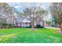 Traditional brick home featuring a lush green lawn, mature trees, and a classic facade with blue shutters at 340 Tradewinds Ln, York, SC 29745