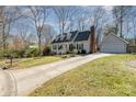 Exterior of a charming house with a long driveway, detached garage, and mature trees on a sunny day at 6525 Castlegate Dr, Charlotte, NC 28226