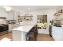 Open-concept kitchen with white cabinets, quartz countertops, wooden floors, and bar seating at 6525 Castlegate Dr, Charlotte, NC 28226