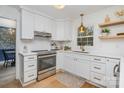Bright, modern kitchen with white cabinets, stainless steel appliances, quartz countertops, and wooden floating shelves at 6525 Castlegate Dr, Charlotte, NC 28226