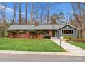 Charming brick and siding home with well-manicured lawn, mature trees, and a stone walkway at 105 Hillside Dr, Davidson, NC 28036