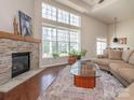 Cozy living room with a stone fireplace, hardwood floors, and large windows at 13245 Chelsea Ridge Ln, Huntersville, NC 28078