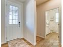 Inviting foyer with a front door and a view into a well-lit, modern bathroom with white fixtures at 2513 Crimson Way, Monroe, NC 28112