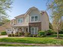 Inviting two-story home with stone details, a covered porch, an attached two-car garage, and a well-maintained lawn at 3216 Bridgewick Rd, Waxhaw, NC 28173