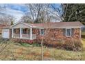 Classic brick home with attached garage, a covered front porch and mature trees at 821 Cabaniss Dr, Shelby, NC 28150