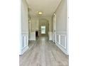 Hallway with hardwood floors, grey walls, white trim, wainscoting, and an arched doorway leading to another room at 8812 Glenover Cir, Charlotte, NC 28269
