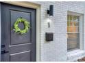 Close up of the front door, showing wreath, black fixtures, and white brick at 921 Ambassador St # 1, Charlotte, NC 28208