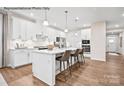 Modern kitchen features white cabinets, stainless appliances, island with seating, and hardwood floors at 1809 Ab Moore Jr Dr # 3238, Indian Trail, NC 28079