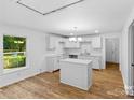 Bright kitchen features an island, white cabinets, stainless steel fixtures, and hardwood flooring at 332 Mountain View St, Gastonia, NC 28052