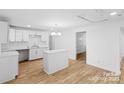 Bright kitchen features an island, white cabinets, stainless steel fixtures, and hardwood flooring at 332 Mountain View St, Gastonia, NC 28052