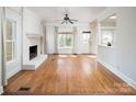 Bright living room features hardwood floors, a painted brick fireplace, large windows, and neutral decor at 7007 Chapparall Ln, Charlotte, NC 28215