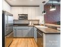 Modern kitchen features stainless appliances, two-tone cabinets and brick accent wall at 710 W Trade St # 314, Charlotte, NC 28202