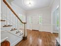 Bright foyer boasts hardwood floors, staircase with wooden banister, classic wainscoting and a front door with sidelights at 7329 Kennington Ct, Charlotte, NC 28270