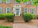 Elegant front door with brick stairs, wrought iron railings, detailed trim, and manicured landscaping at 7329 Kennington Ct, Charlotte, NC 28270