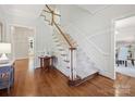 Traditional staircase featuring hardwood floors, white risers, wooden banister and trim, and an elegant, neutral carpet runner at 7329 Kennington Ct, Charlotte, NC 28270