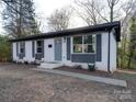 Charming single-story brick home featuring gray shutters, a cozy front entry, and mature trees at 908 Davenport St, Charlotte, NC 28208