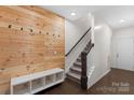 Inviting entryway with wood accent wall and a storage bench leading to the staircase at 9330 Ainslie Downs St, Charlotte, NC 28273