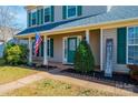 Inviting front porch with an American flag, lush landscaping, and a bright green front door at 102 Brewster Ct, Mooresville, NC 28115
