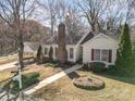 Inviting single-story home with a brick chimney, red shutters, landscaped yard, and detached garage at 457 Birchwood Ne Trl, Concord, NC 28025