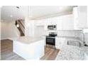 Bright kitchen featuring stainless steel appliances, white cabinets, a stone backsplash, and a kitchen island at 616 Smith St # B, Mooresville, NC 28115
