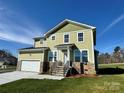 Two story home with a green exterior, stone accents, two car garage, and front porch at 1022 Heath Helms Rd, Monroe, NC 28110