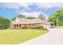 Brick home with a three-car garage and RV shelter, surrounded by lush greenery and mature trees at 119 Era St, Troutman, NC 28166