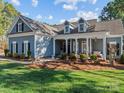 A charming blue home featuring a welcoming front porch with classic columns and manicured landscaping at 1742 Verdict Ridge Dr, Denver, NC 28037