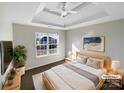 Serene main bedroom featuring a tray ceiling, a large window with sunlit view, and soft, neutral decor at 215 Madelia Pl, Mooresville, NC 28115