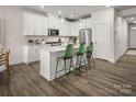 Modern kitchen featuring white cabinetry, an island with green chairs and stainless appliances at 3020 Finchborough Ct # 230, Charlotte, NC 28269