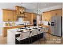 Modern kitchen features a large island with seating, pendant lighting, stainless steel appliances, and light wood cabinets at 6005 Valehaven Pl # 0049, Charlotte, NC 28269