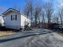 A single-story house with gray siding, gravel driveway, a storage shed, and a red car nearby at 109 Hummingbird Cir, New London, NC 28127