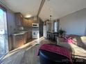 Cozy living room with a couch, ottoman, kitchen, and dining table, filled with natural light at 109 Hummingbird Cir, New London, NC 28127