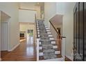 Bright foyer featuring hardwood floors, staircase with carpet runner, and views into the living spaces at 12724 Cliffcreek Dr, Huntersville, NC 28078