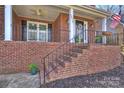 Inviting front porch with brick steps, wrought iron railing, columns, and an American flag on display at 12724 Cliffcreek Dr, Huntersville, NC 28078