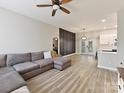 Bright living room with a sectional sofa, wood floors, and a ceiling fan with adjoining modern kitchen at 1923 Gables Dr, Monroe, NC 28112