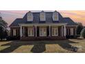 Charming brick home featuring a welcoming front porch with columns and dormer windows at sunset at 2968 Robinwood Rd, Gastonia, NC 28054