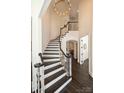 Elegant staircase with dark wood steps and white risers, and a modern chandelier, adding a touch of sophistication at 5225 Lila Wood Cir, Charlotte, NC 28209