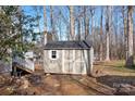 Outdoor shed with gray siding, a shingled roof, and a functional door and window at 11121 Timber Hill Ct, Charlotte, NC 28226