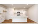 Modern kitchen with stainless steel appliances, white cabinets, a large kitchen island and hardwood floors at 130 Woodhall Way, Troutman, NC 28166