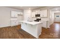 Bright and airy kitchen featuring a center island, white cabinetry, stainless appliances and hardwood floors at 130 Woodhall Way, Troutman, NC 28166