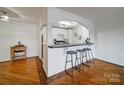 Eat-in kitchen featuring hardwood floors, a breakfast bar, and white cabinetry at 1323 Queens Rd # 424, Charlotte, NC 28207