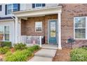 Inviting covered front porch with seating area, brick exterior, and blue front door at 13319 Jacks Ln, Pineville, NC 28134