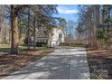 View of a long concrete driveway leading up to a two-story home with attached garage at 15314 Logan Grove Rd, Charlotte, NC 28227