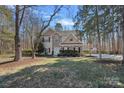 View of a two-story home with a long driveway, a lawn, and mature trees at 15314 Logan Grove Rd, Charlotte, NC 28227