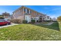 A row of brick townhomes with manicured lawns, dark shutters, and bay windows beneath a clear blue sky at 5472 Ives Nw St, Concord, NC 28027