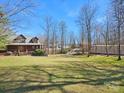 Expansive front yard showcasing lush green grass and mature trees surrounding the charming log home at 5981 Johnson Rd, Lake Wylie, SC 29710